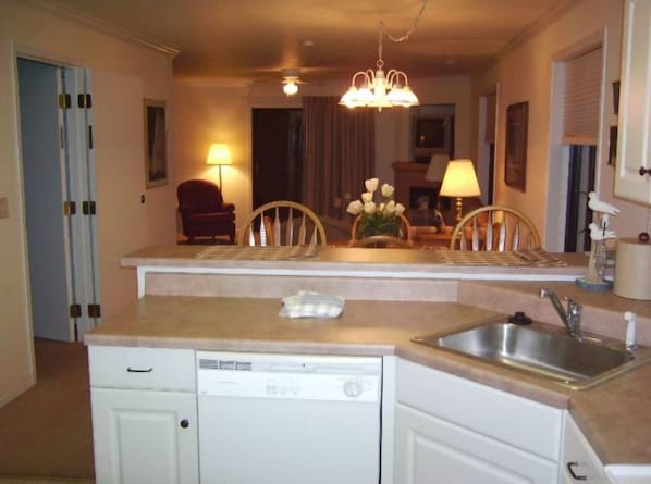 A compact kitchen with a dishwasher, sink, and a dining area with chairs and a table.