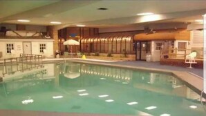 Une piscine intérieure dotée d’un plongeoir, d’un vestiaire et d’un espace détente avec des fauteuils.