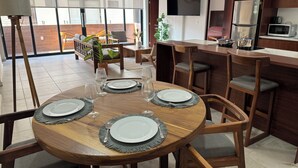 Comedor con una mesa redonda de madera dispuesta para cuatro personas, rodeada de sillas de madera con cojines grises.