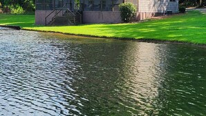 A house with a covered porch, a small lawn, and a body of water in front.