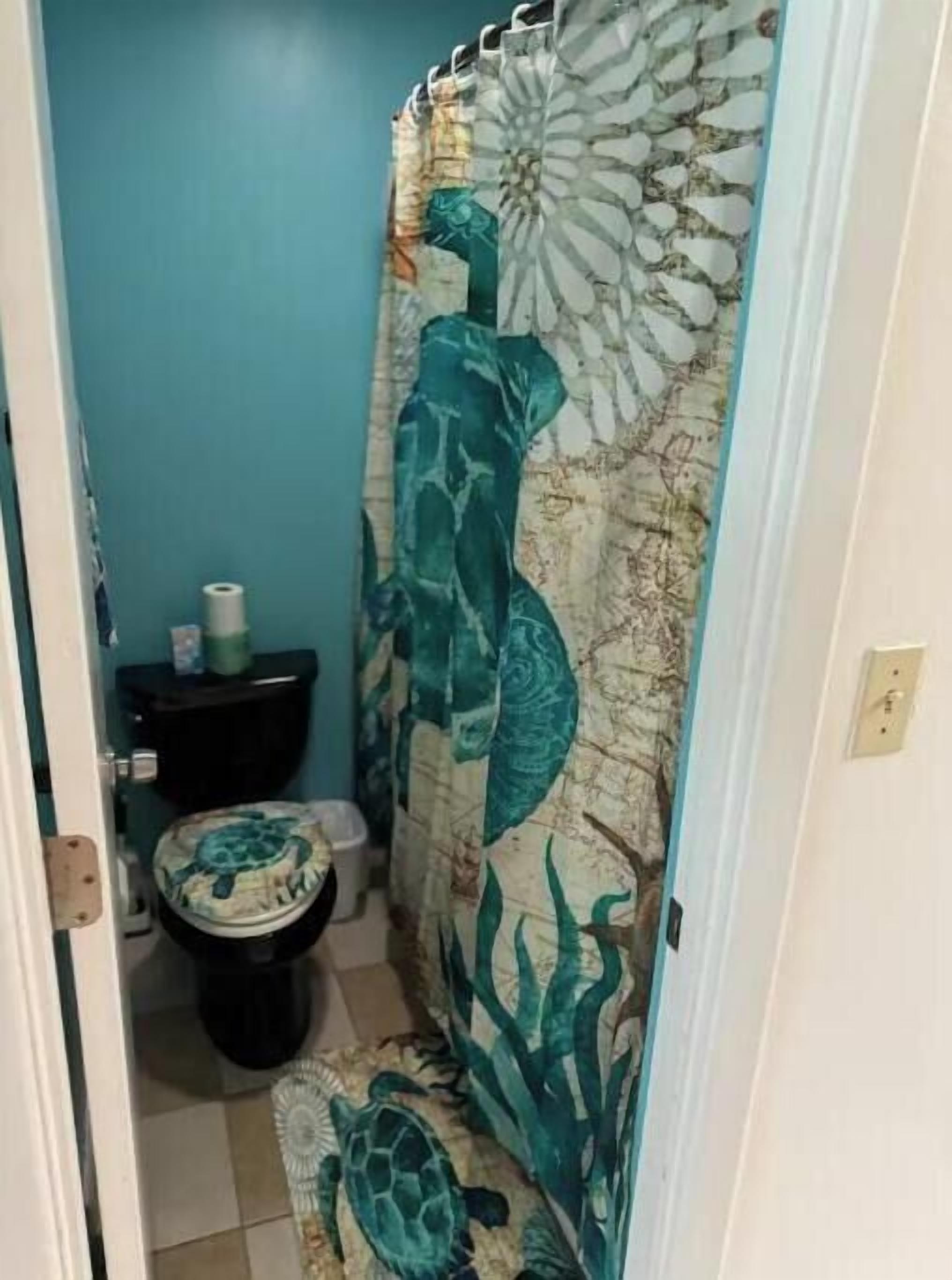 Une salle de bain équipée de toilettes, d’un lavabo et d’un rideau de douche orné d’un motif représentant une tortue de mer.