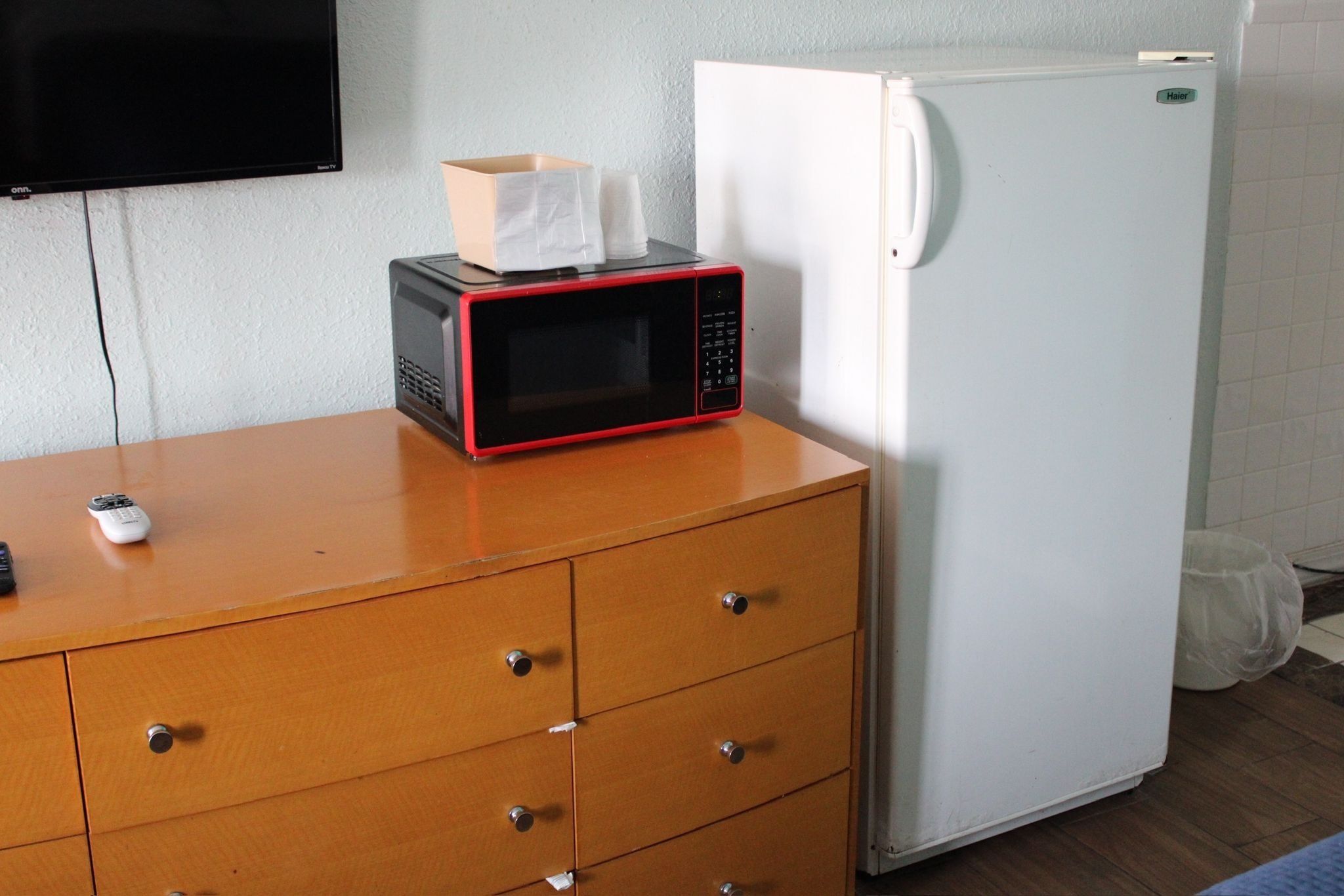 Una kitchenette con microondas, refrigerador y un mueble de madera.