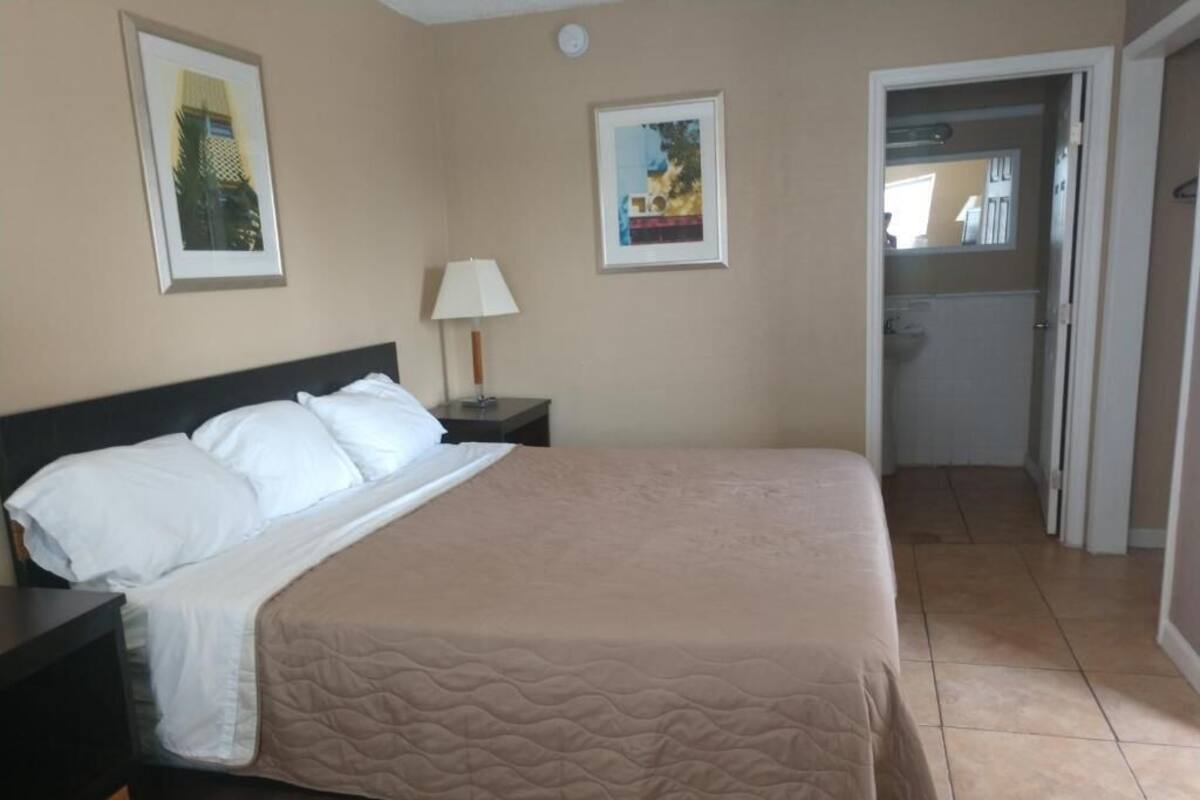 A bedroom with a bed, nightstand, lamp, and two framed pictures on the wall.