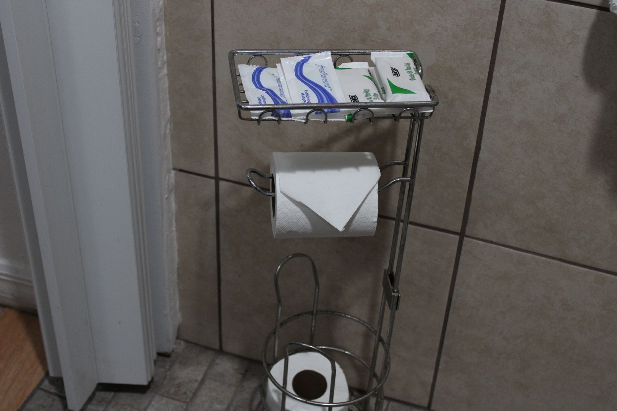 A metal rack with toilet paper and paper towels in a bathroom.