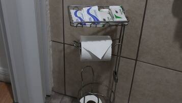 A metal rack with toilet paper and paper towels in a bathroom.
