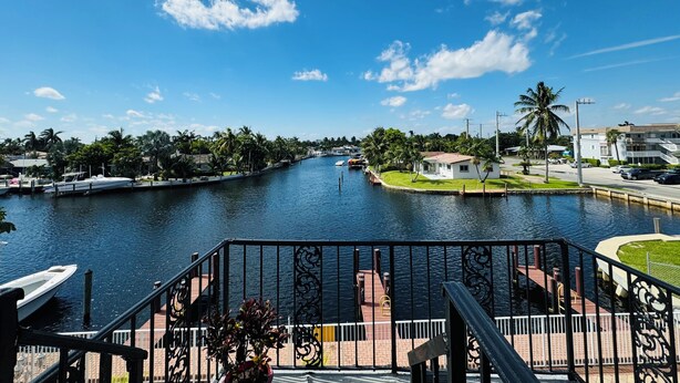 A waterfront view with a river, a bridge, and a white building with a red roof. - Executive Economy Lodge (Pompano Beach)