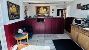 A kitchen with a marble countertop, a black rug, and a ceiling with a light fixture. - Executive Economy Lodge (Pompano Beach)