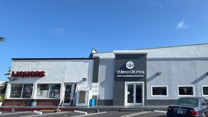 A building with a liquor store and a pizza lounge. - Executive Economy Lodge (Pompano Beach)