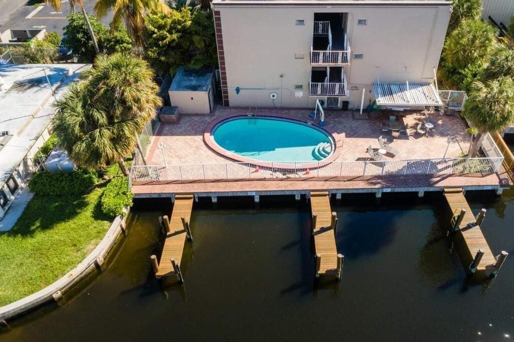 Vista aérea de un edificio con piscina, un patio cubierto y un muelle que se adentra en el agua.