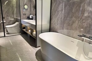 A modern bathroom with a freestanding bathtub, a toilet, and a vanity with a mirror. - Nanshan Hotel (Panzhihua)