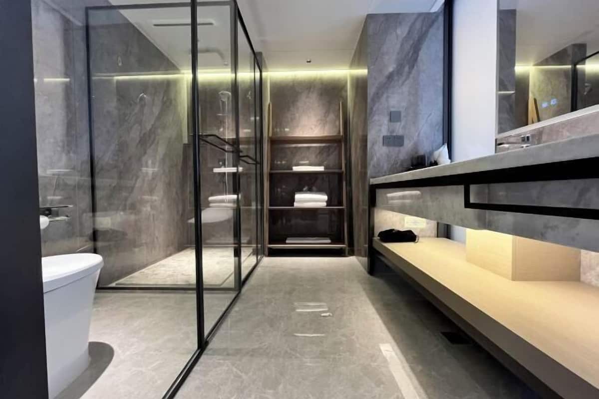 A modern bathroom with a glass shower enclosure, a toilet, and a vanity with a mirror.