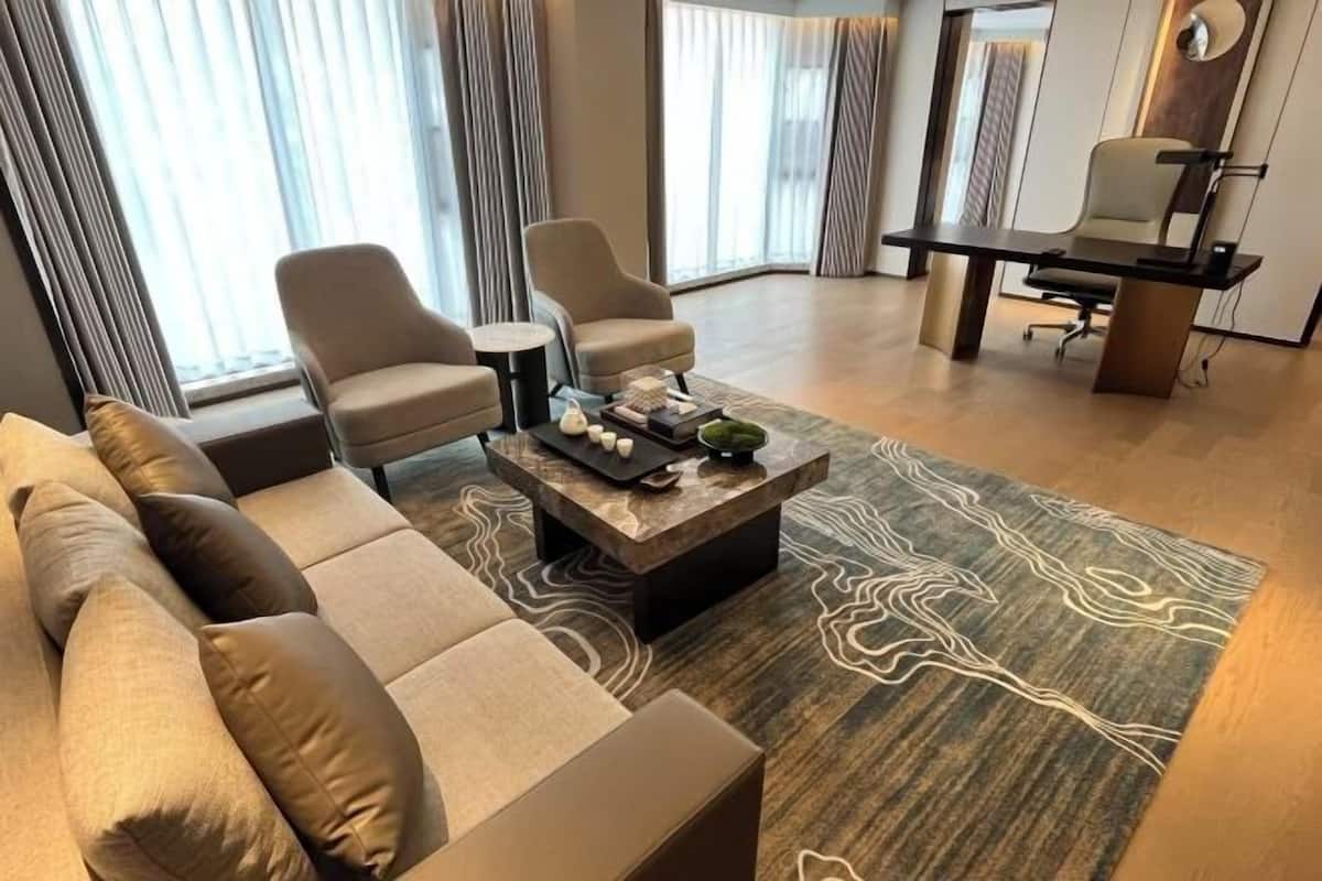 A modern living room with a sofa, two armchairs, a coffee table, and a desk.