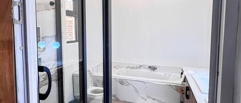 Superior studio suite, uitzicht op tuin | Badkamer | Een aparte badkuip en douche, een regendouche, handdoeken, toiletpapier