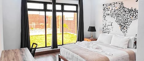 A modern bedroom with a large bed, a desk, and a ceiling fan.
