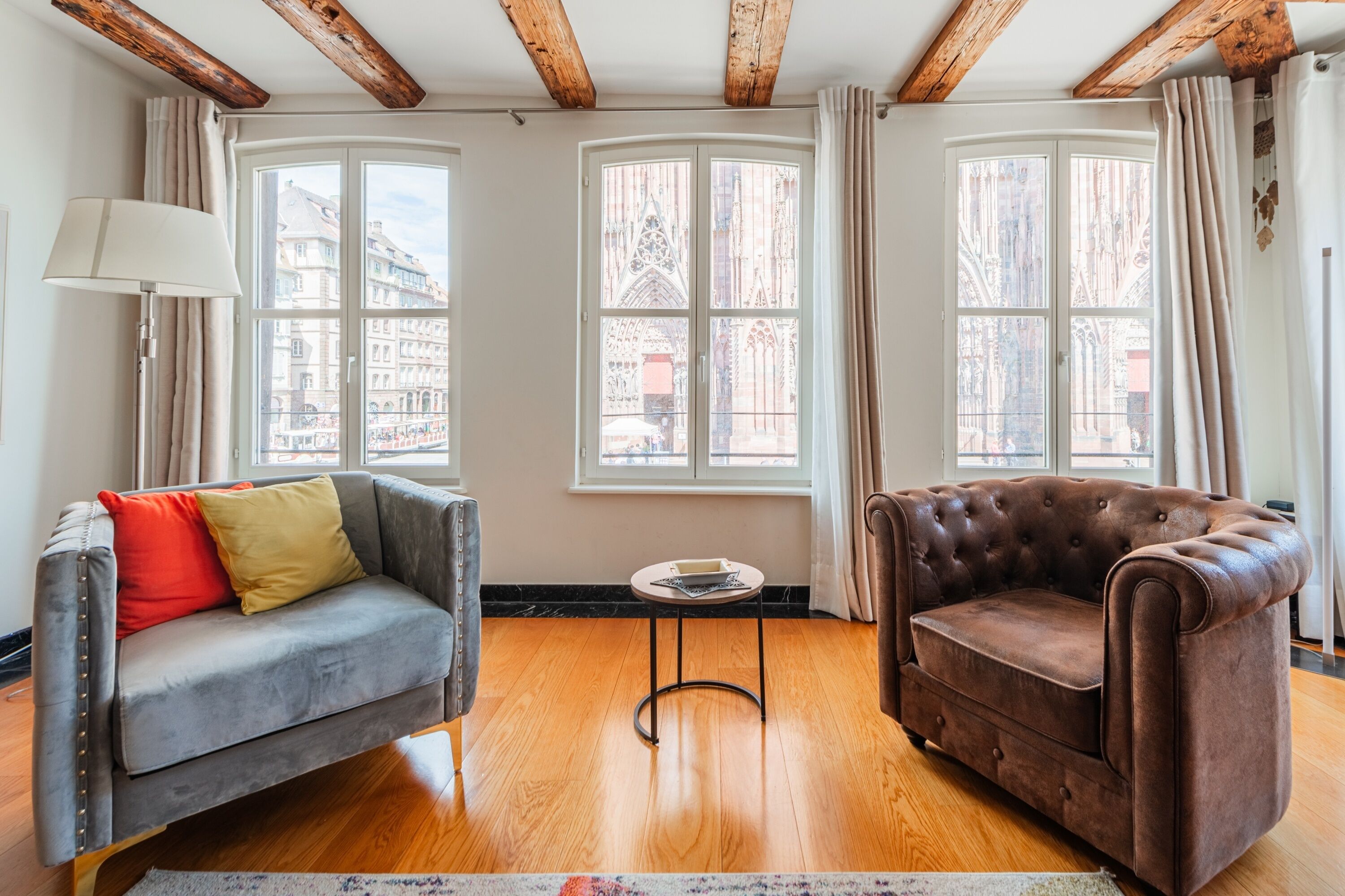 A room with a grey sofa, a brown armchair, and a small round table.