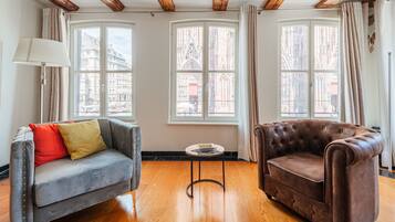 A room with a grey sofa, a brown armchair, and a small round table.