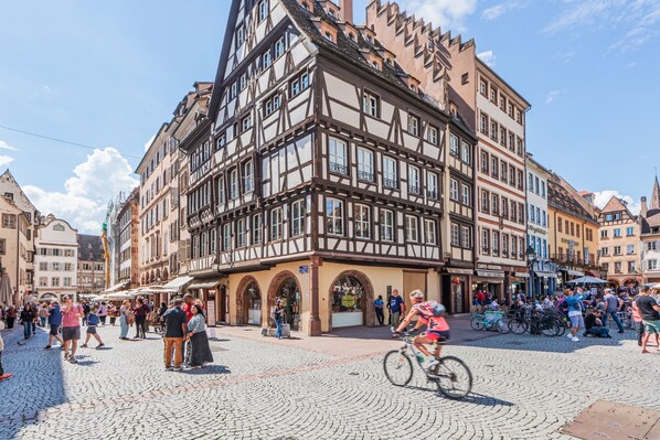 A cobblestone square with historic buildings, a cyclist, and people walking.