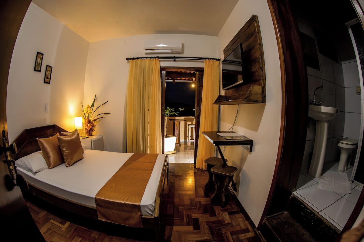 Hotelkamer met een bed, bureau met lamp, een bloempot en uitzicht.