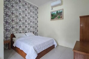 Un dormitorio con pared estampada, una cama, una mesita de noche, un armario de madera y un cuadro en la pared.