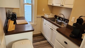 A compact kitchen with white cabinets, a countertop, a sink, a trash can, and a coffee maker. - Very spacious, clean, and comfortable first floor unit. Close to major highway!  (Manchester)