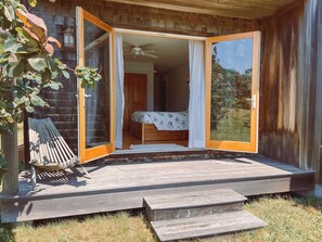 Une cabane en bois dotée d’une terrasse en bois, d’un lit à baldaquin et offrant une vue sur l’extérieur.