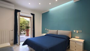 Quarto com cama, mesas de cabeceira e vista para o exterior.
