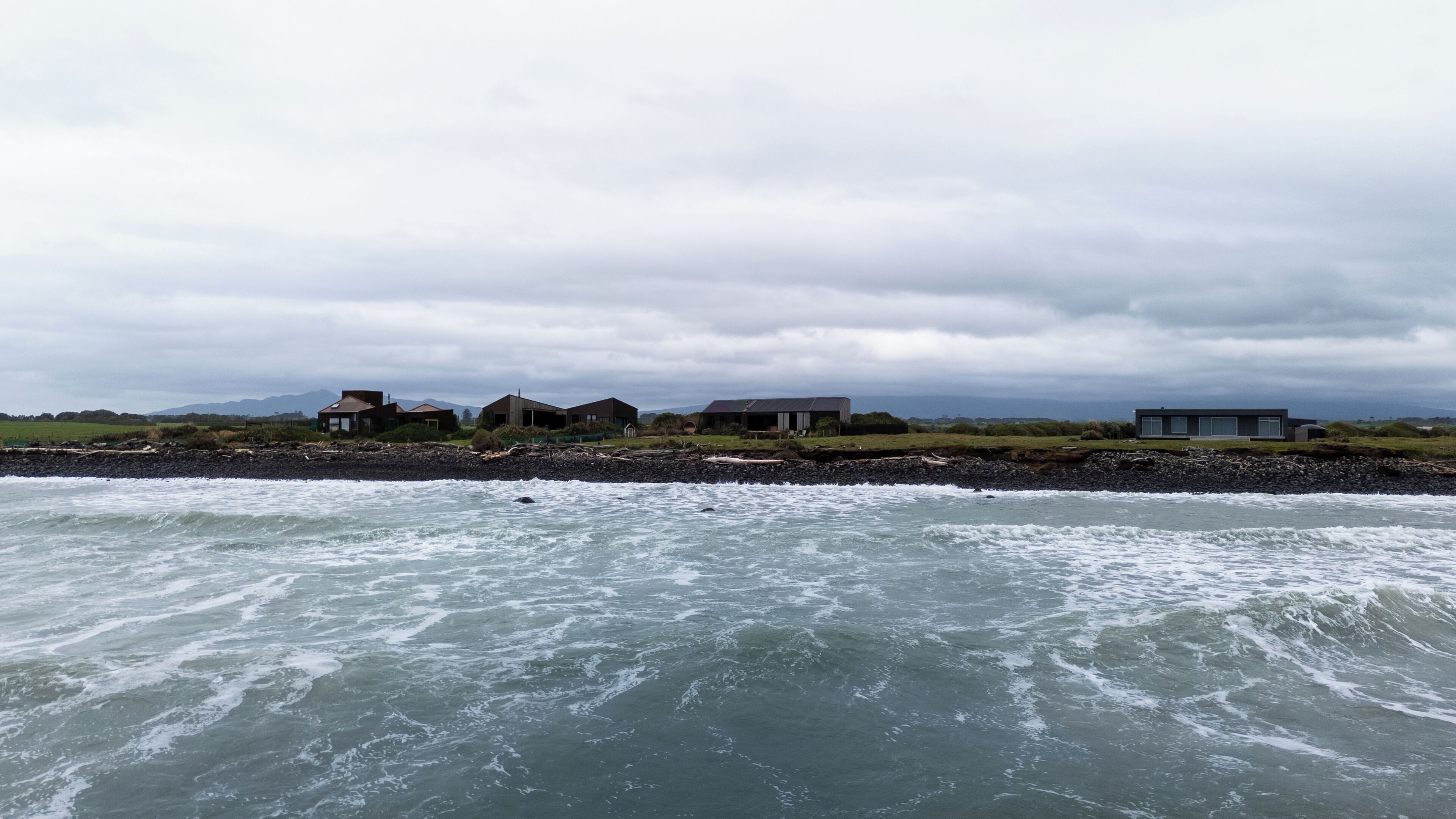 Ett område vid kusten med flera moderna hus längs strandlinjen.