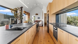 A modern kitchen with wooden cabinets, a black countertop, and a view of the outdoors.