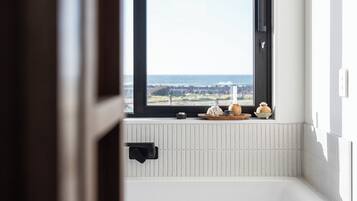 Een badkamer met een groot raam, een badkuip en een handdoekhouder.