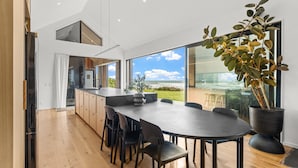 A modern kitchen with wooden cabinets, a large island with seating, and a view of the outdoors.