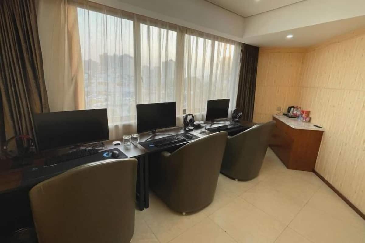 A modern office space with a long table, multiple computer monitors, and ergonomic chairs.