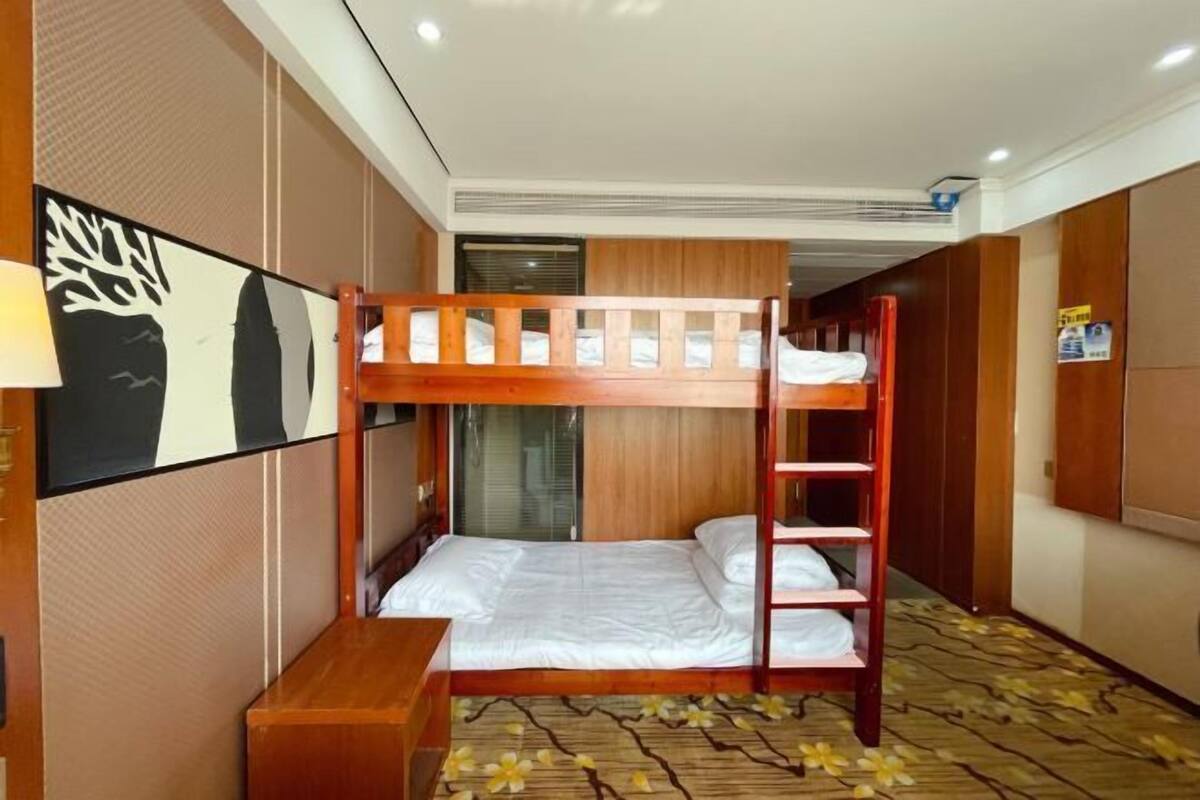 A bunk bed room with a wooden ladder, a small wooden table, and a wall-mounted shelf.