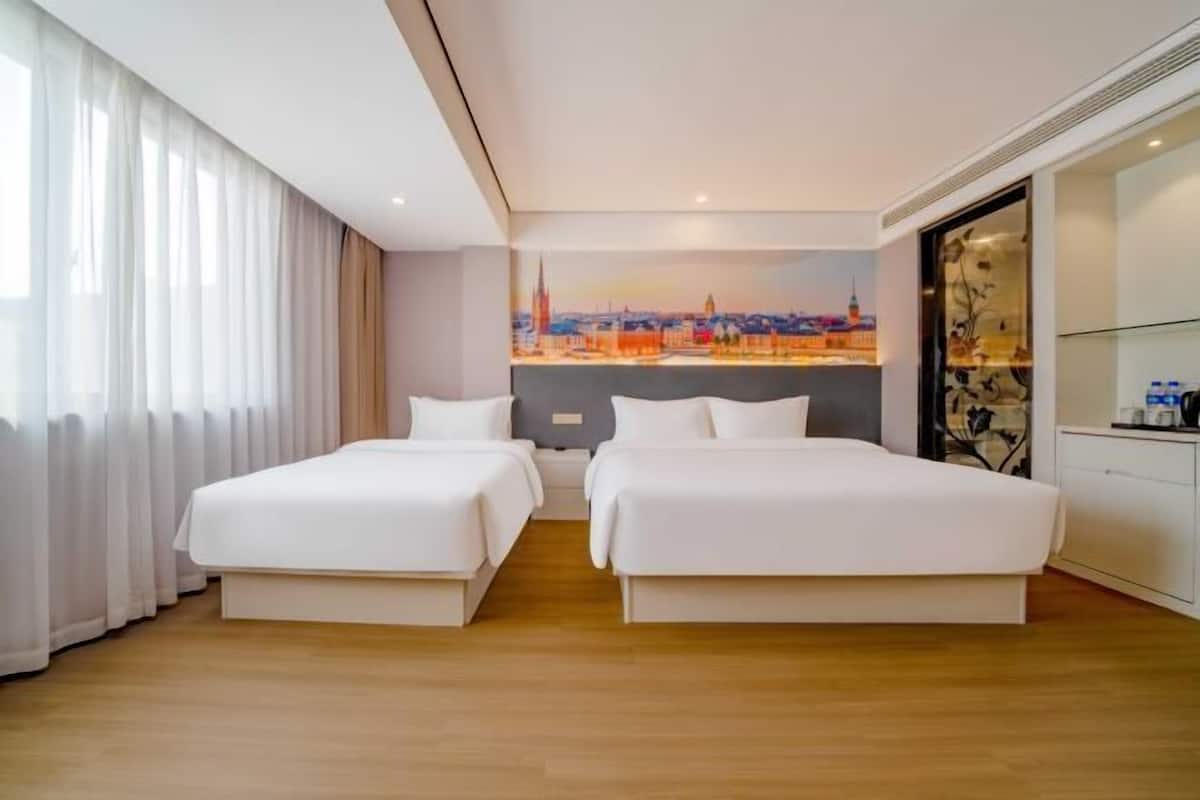 A hotel room with two beds, a cityscape mural, and a minibar.