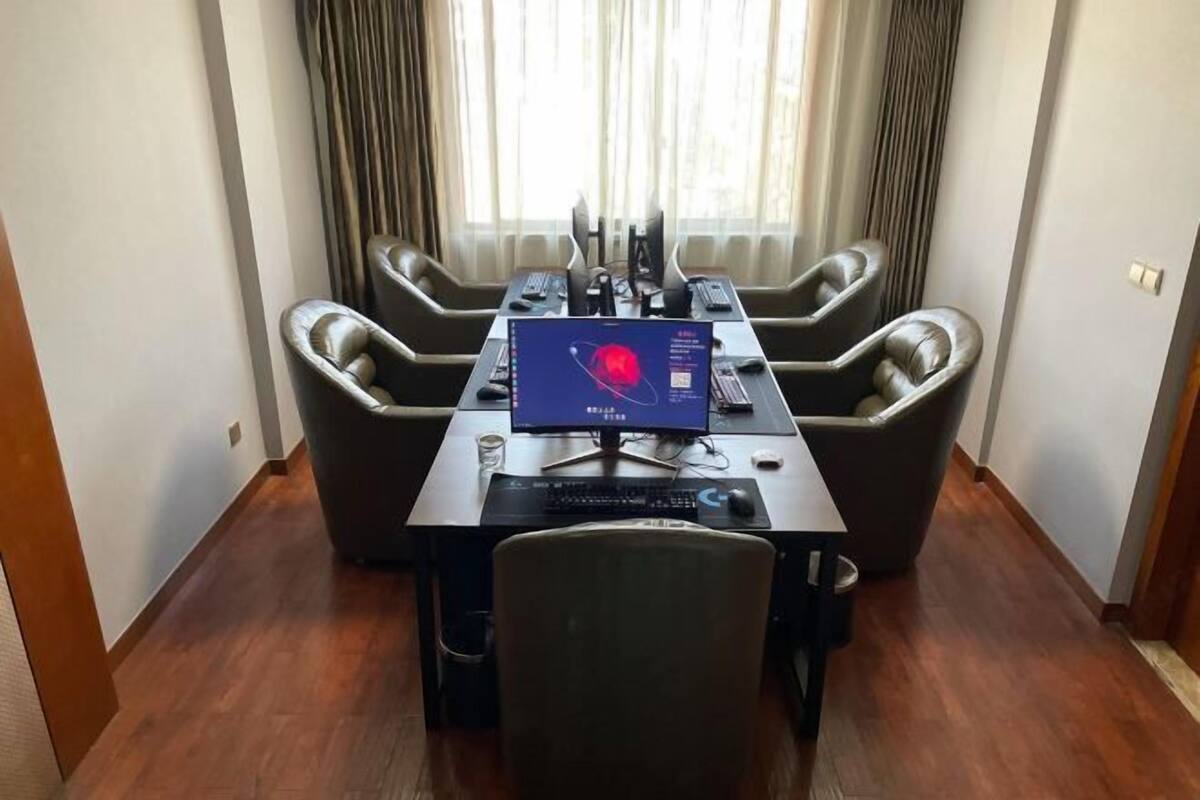 A conference room with a large table, multiple chairs, a computer, and a monitor.