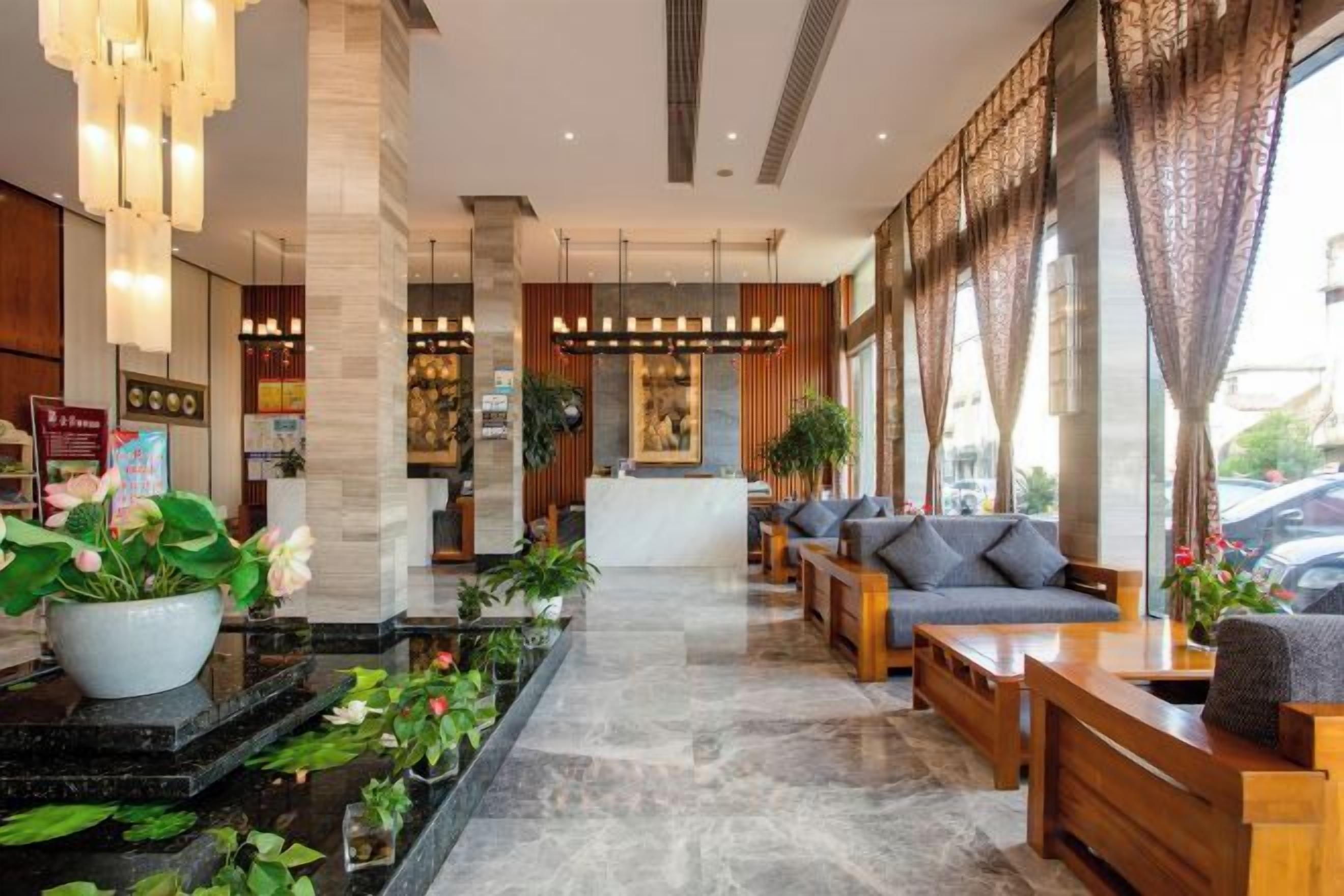 A hotel lobby with a reception desk, seating area, and potted plants.