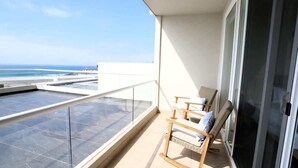 A balcony with a view of the sea, a glass door, and a wooden chair. - Jolla Excellence 3bd 2b Rosarito (Playas de Rosarito)