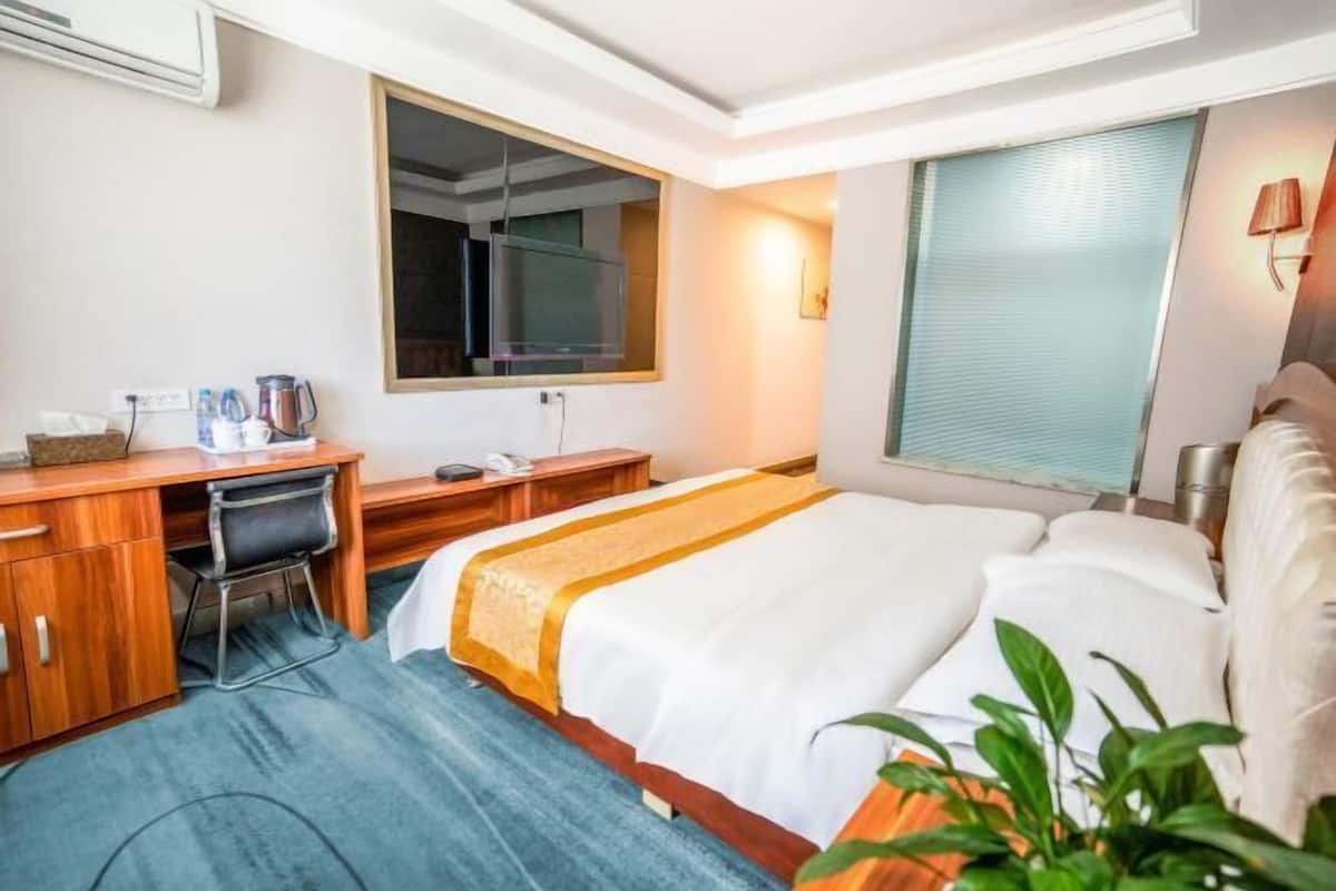 Una habitación de hotel con cama, escritorio, silla y un espejo grande.