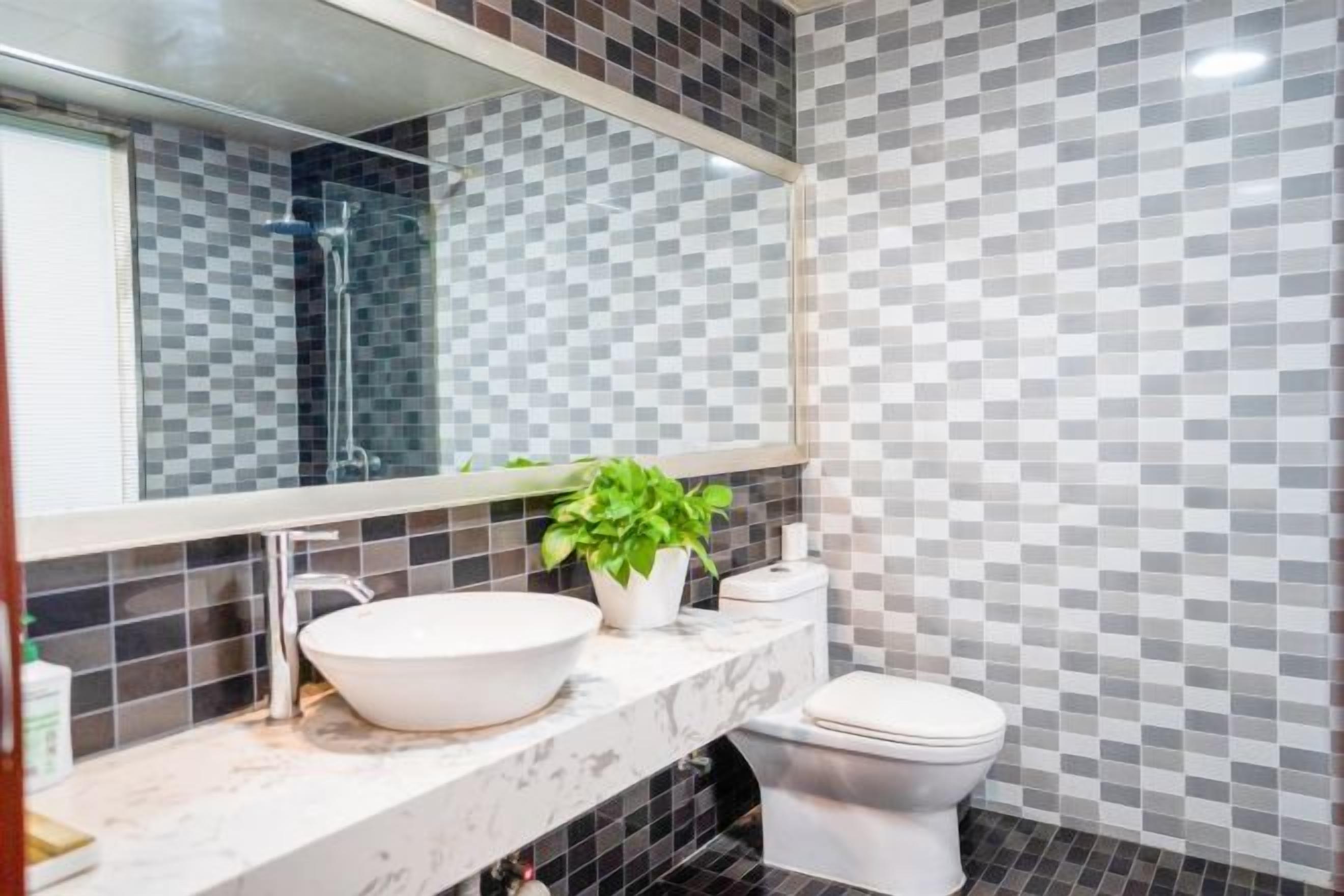 A bathroom with a white sink, a toilet, a mirror, and a potted plant.