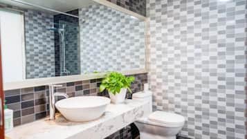 A bathroom with a white sink, a toilet, a mirror, and a potted plant.