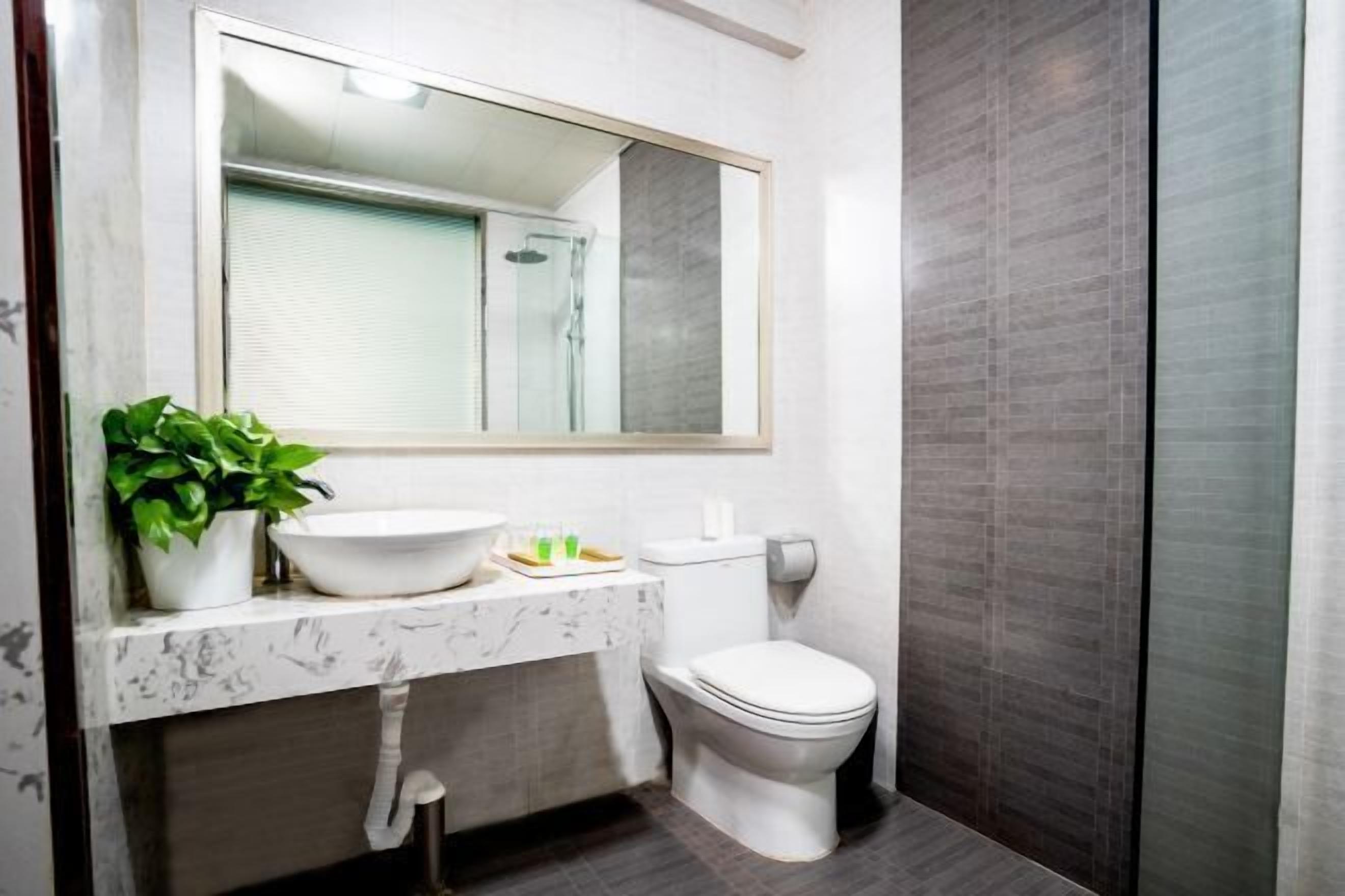Een moderne badkamer met een marmeren wastafel, toilet en douche.