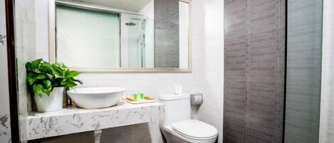 A modern bathroom with a marble sink, a toilet, and a shower.