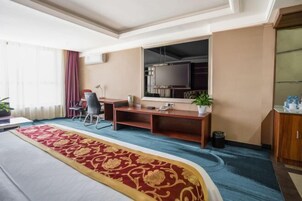 Una habitación de hotel con una cama, un escritorio, una silla, un televisor y una planta.