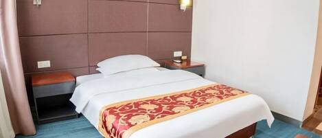 A hotel room with a bed, a nightstand, a lamp, and a wooden bench.