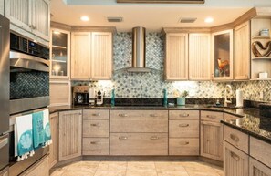 Una cucina con mobili in legno, una cappa aspirante in acciaio inossidabile e un backsplash decorato.
