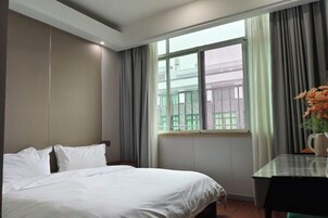 Una habitación de hotel con cama, una mesa y una ventana con cortinas.
