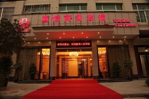 A hotel entrance with a red carpet leading to the doors, a signboard with Chinese characters, and a chandelier above the entrance. - Tangyun Business Hotel (Pingyang)