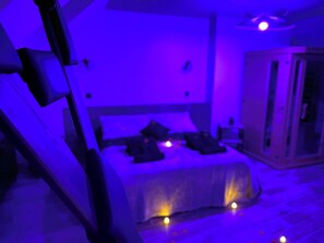 A bedroom with a bed, bedside tables, and a wardrobe. - Love Room Le Chalet / Jacuzzi / Sauna (Château-Landon)