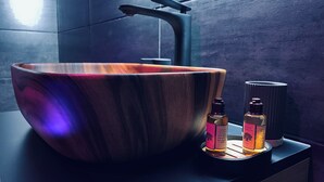 Une salle de bain moderne avec un grand lavabo en bois, deux bouteilles de shampoing et un porte-serviettes.