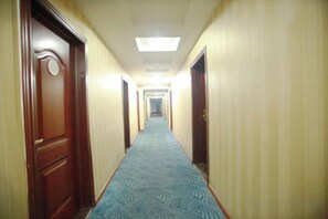 Pasillo de hotel con puertas a ambos lados, piso alfombrado y una lámpara en el techo.