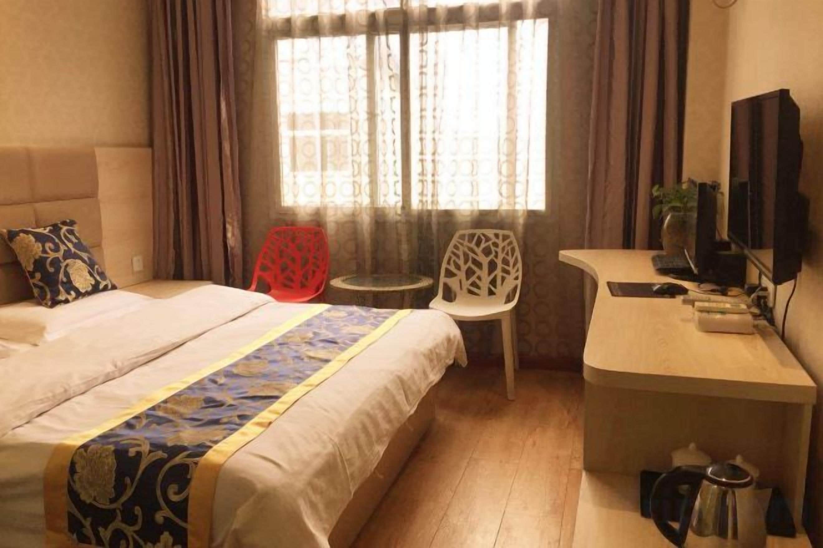 Ein Hotelzimmer mit Bett, Schreibtisch, Stuhl und Fernseher.
